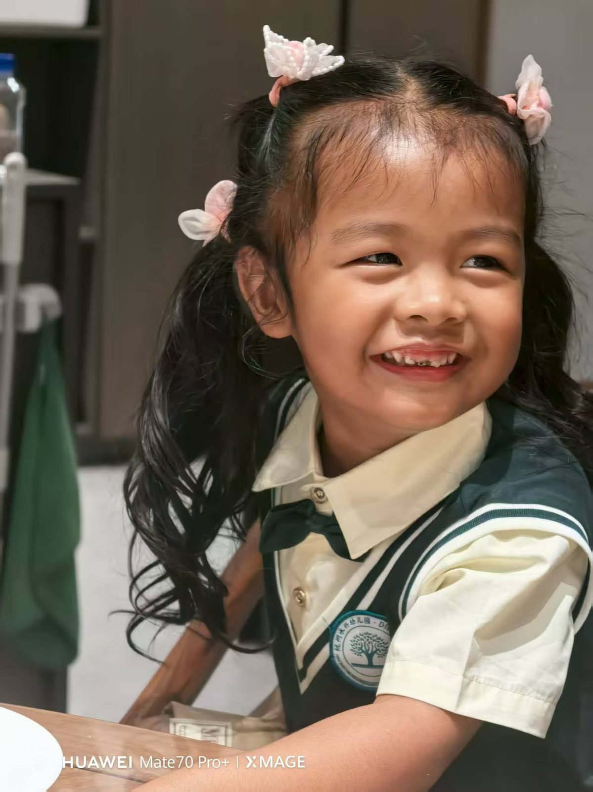 幼儿园园服穿得整整齐齐，头发扎了三个小揪揪，露出缺了门牙的笑容。