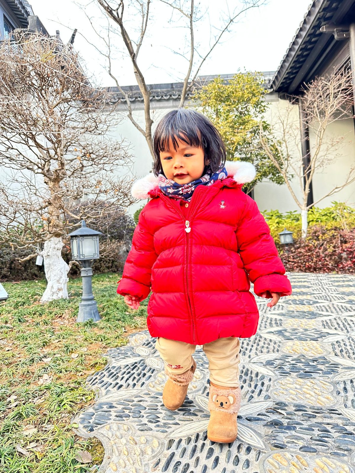 红色羽绒服+小熊雪地靴，在石子路上走得很稳——冬天也要出门！