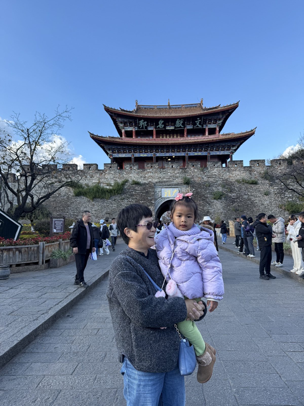 在云南香格里拉古城的牌楼前，外婆抱着阿雅拍张照